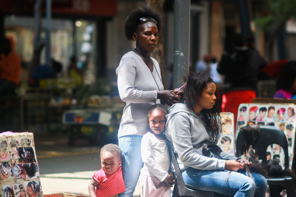 ©Dahlia Maubane. Rosetta and her two beautiful grandchildren. She has been working at Kerk Street market for 22 years. She is raising two generations with the money she makes with her craft.  From the series Woza S